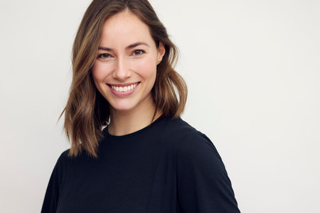 Portrait of beautiful woman, smiling and looking in camera with white teeth. Close-up portrait of cute female girl in black t-shirt isolated on white background.の写真素材