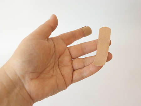 cut index finger taped with adhesive plaster. on a white background.の写真素材