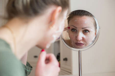 Cosmetic face mask and girl look in the mirrorの写真素材