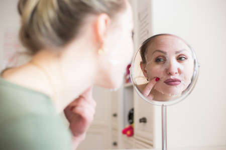 Cosmetic face mask and girl look in the mirrorの写真素材