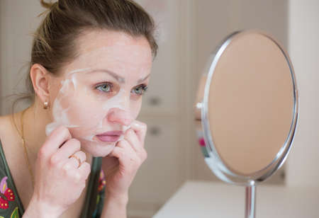Cosmetic face mask and girl look in the mirrorの写真素材