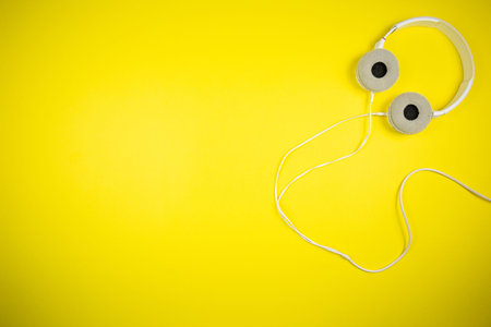 White audio headphones with a 3.5 mm wire on a yellow backgroundの写真素材