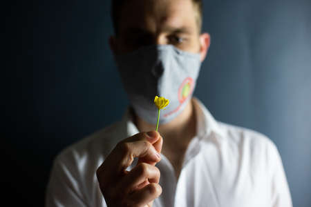 The man in the mask "Stop Coronavirus" sniffs the smell of a fresh flower, COVID-19の写真素材