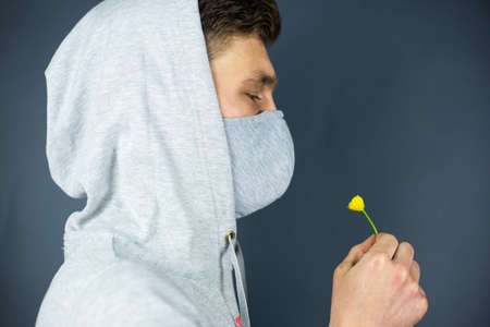 The man in the mask "Stop Coronavirus" sniffs the smell of a fresh flowerの写真素材