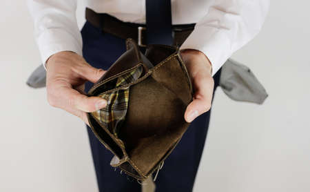 A man in a business suit holds in his hands an empty wallet without money. Financial crisis. Bankruptcy in business. The employer is disappointed.の写真素材