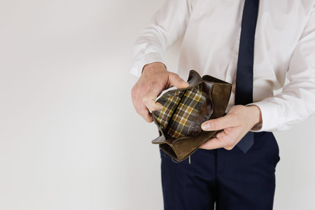 A man in a business suit holds in his hands an empty wallet without money. Financial crisis....