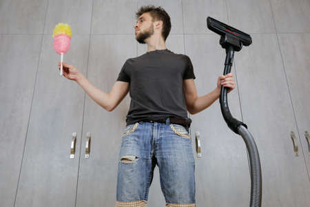 A man with a dust brush and a vacuum cleaner. House cleaning.の写真素材