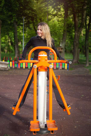The girl on the summer sports ground does sports exercises on the stepper. Healthy lifestyle.の写真素材