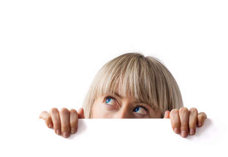 Young woman hiding behind blank white board and looking upの写真素材