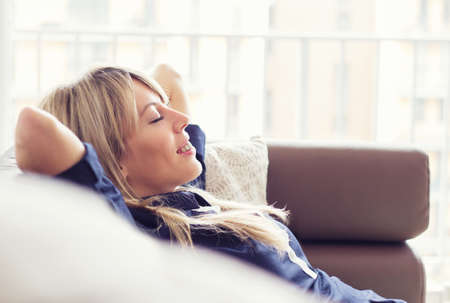 Relaxed young woman lying on couchの写真素材