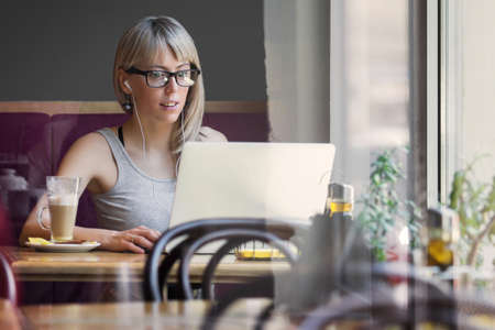 Young woman working with computer in cafeの写真素材