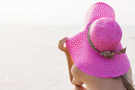 Young woman with beach hat looking into distance  の写真素材