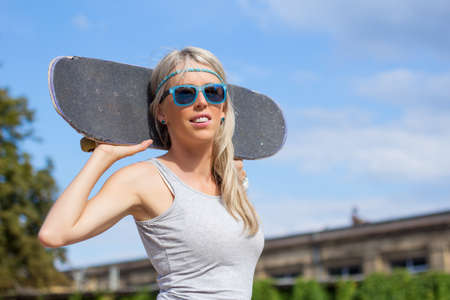 Young girl standing and holding skateboard behind her headの写真素材