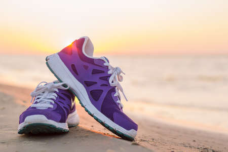 Pair of running shoes on the beach at sunsetの写真素材
