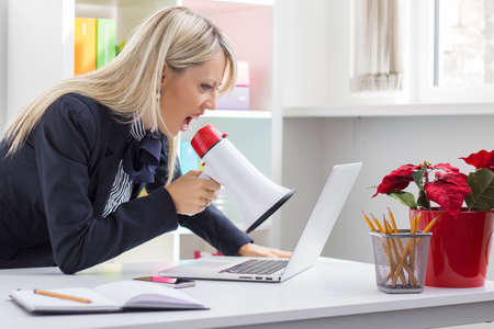 Woman yelling to her computer on megaphoneの写真素材