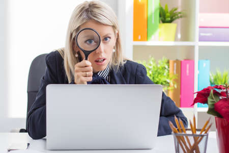 Woman looking at you through a magnifying glassの写真素材