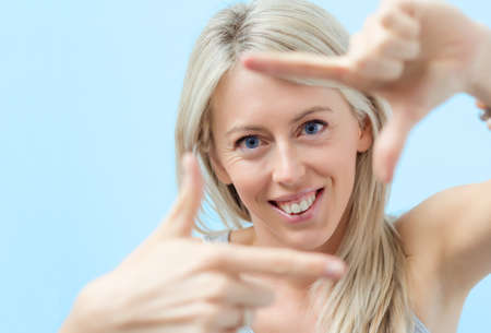 Young woman making selfy photo frame around her faceの写真素材