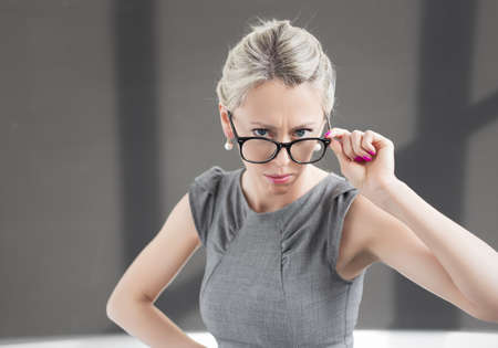 Strict teacher looking through glasses with serious expressionの写真素材