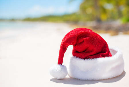 Red Santa Claus hat on beach, theme for Christmas vacation and travelの写真素材