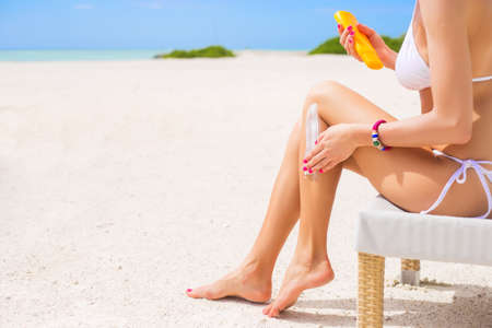 Woman using sunscreen on the beachの写真素材