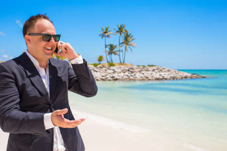 Businessman talking on phone at the beachの写真素材