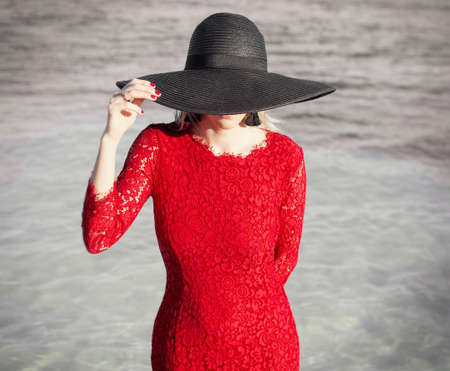 Woman in red dress and black hatの写真素材