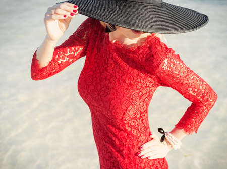 Stylish woman wearing red dress and black hatの写真素材