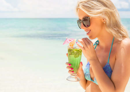 Young woman drinking mojito cocktail on the beachの写真素材