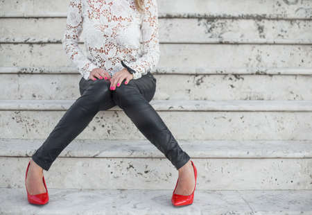 Sexy lady in red high heel shoes sitting on stairsの写真素材