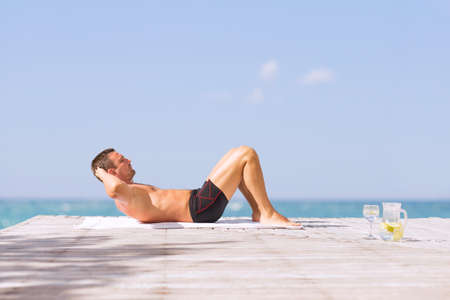 Young fit man doing abs crunches exercise outdoorsの写真素材