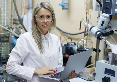 Woman with laptop computer working in chemical labの写真素材