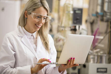 Female chemist working with laptop computer in the labの写真素材
