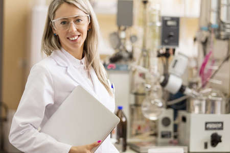 Young chemist with laptop computer standing in chemistry labの写真素材