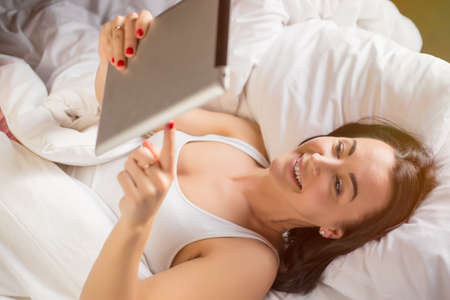 Woman using tablet computer ir bedの写真素材