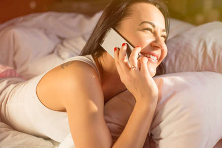 Woman talking on phone in bedの写真素材