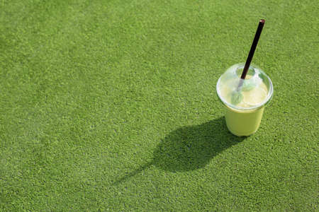 Healthy green smoothie cup on green grassの写真素材