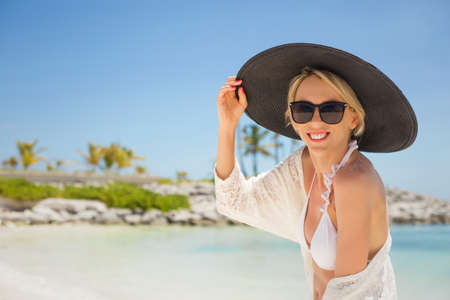 Woman with black summer hat on the beachの写真素材
