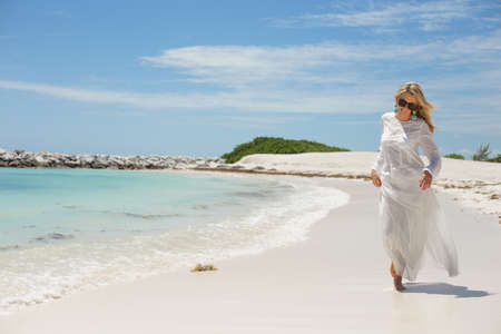 Happy young woman walking on the beachの写真素材