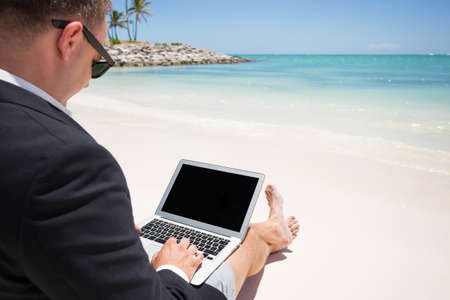 Businessman working with computer on the beachの写真素材