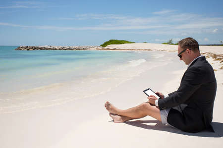 Businessman with digital tablet on the beachの写真素材