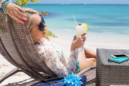 Woman holding glass of cocktail on the beachの写真素材