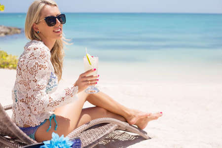 Woman drinking cocktail on the beachの写真素材