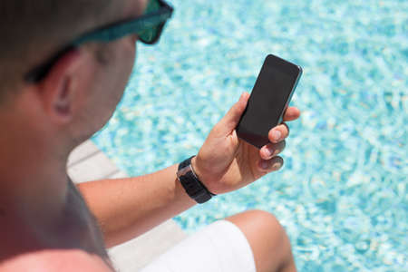 Man using smartphone by the poolの写真素材