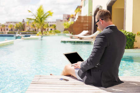 Relaxed businessman working by the poolの写真素材