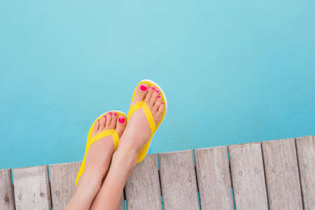 Woman with yellow flip flops by the poolの写真素材