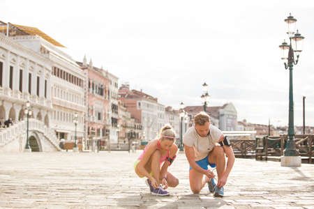 Couple tying shoes before exercising outdoors in the cityの写真素材