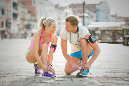 Woman and man tying sports shoes before workoutの写真素材