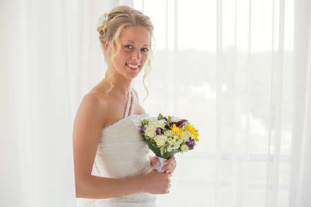 Bride holding a wedding bouquet and smilingの写真素材