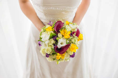 Woman in white holding wedding bouquetの写真素材