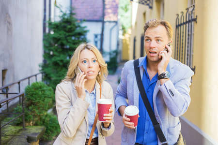 Surprised man and woman talking on the phoneの写真素材
